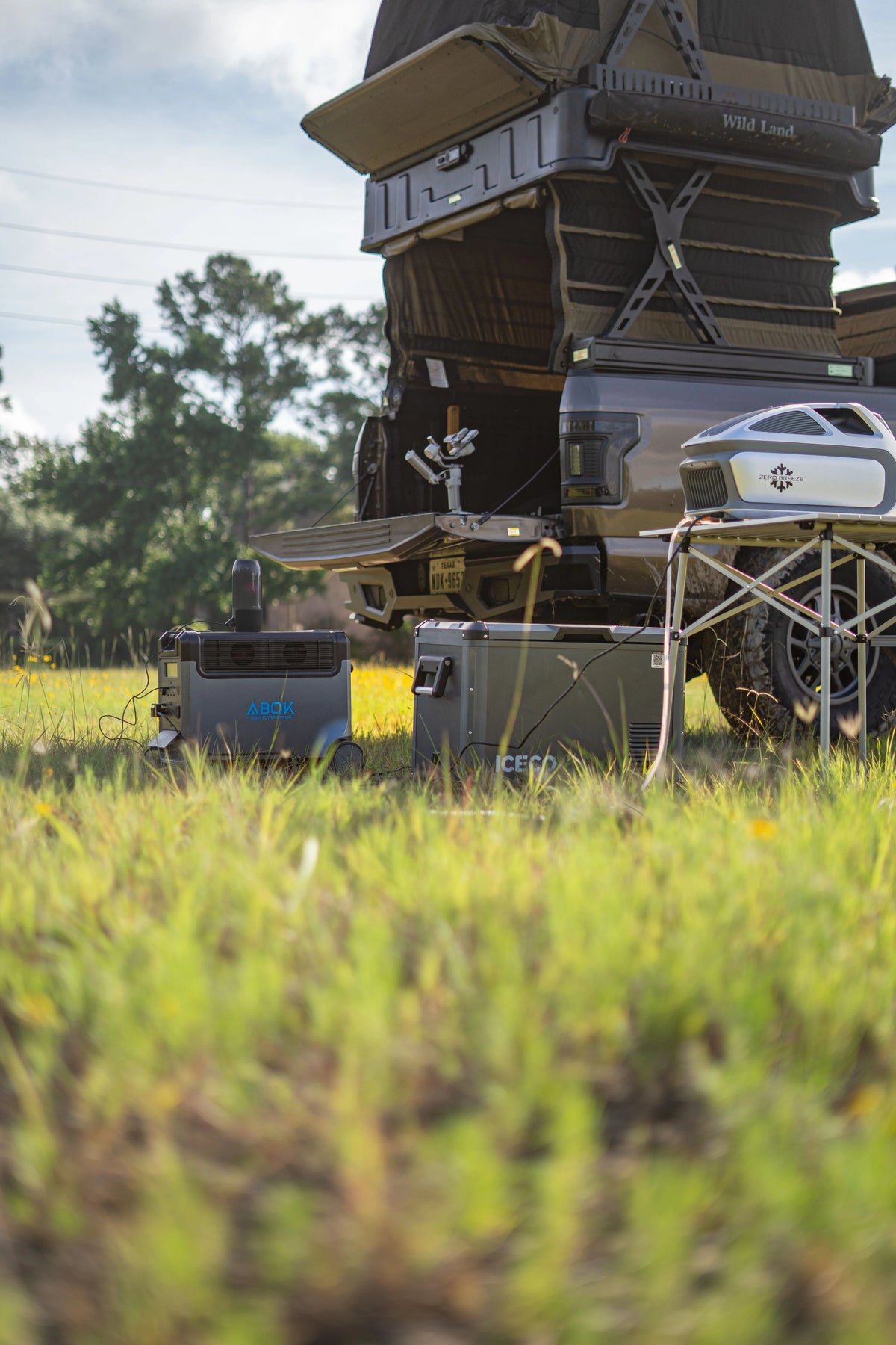 ABOK portable power station beside a vehicle with a rooftop tent at a campsite.